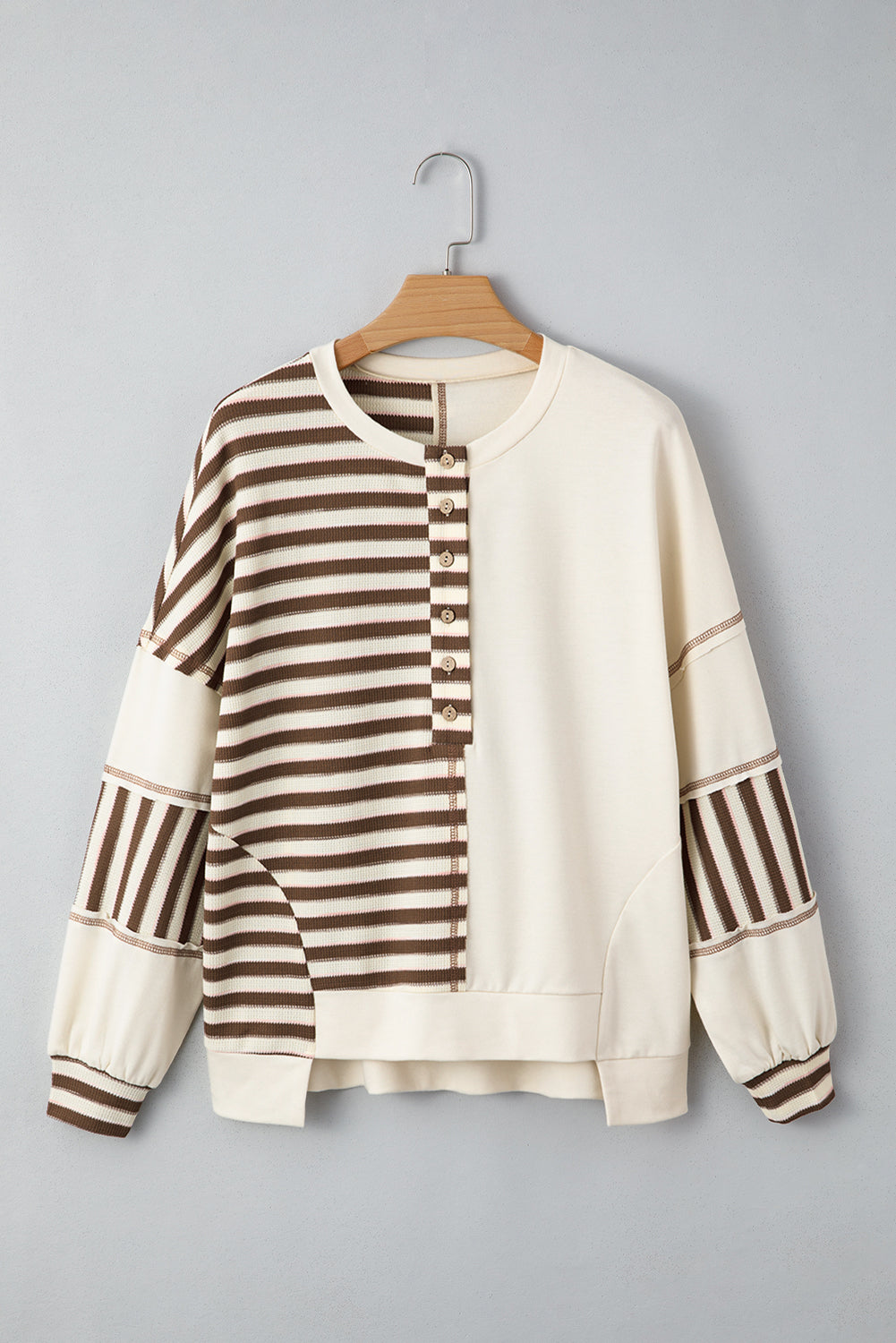 Striped sweater on a hanger against a gray background