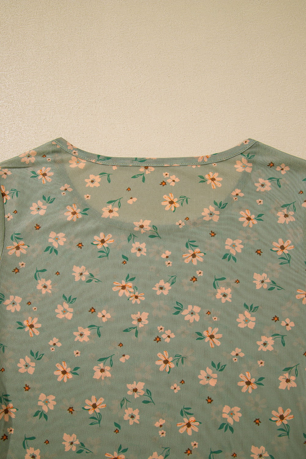 Green t-shirt with floral pattern on a plain background