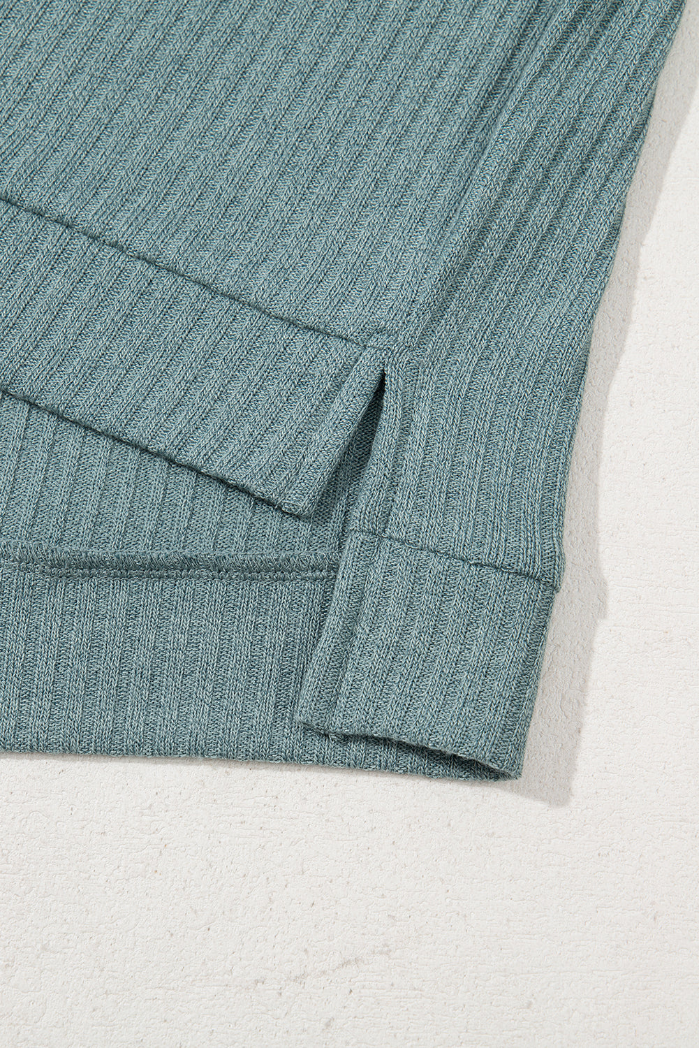 Close-up of a teal ribbed fabric on a light gray background