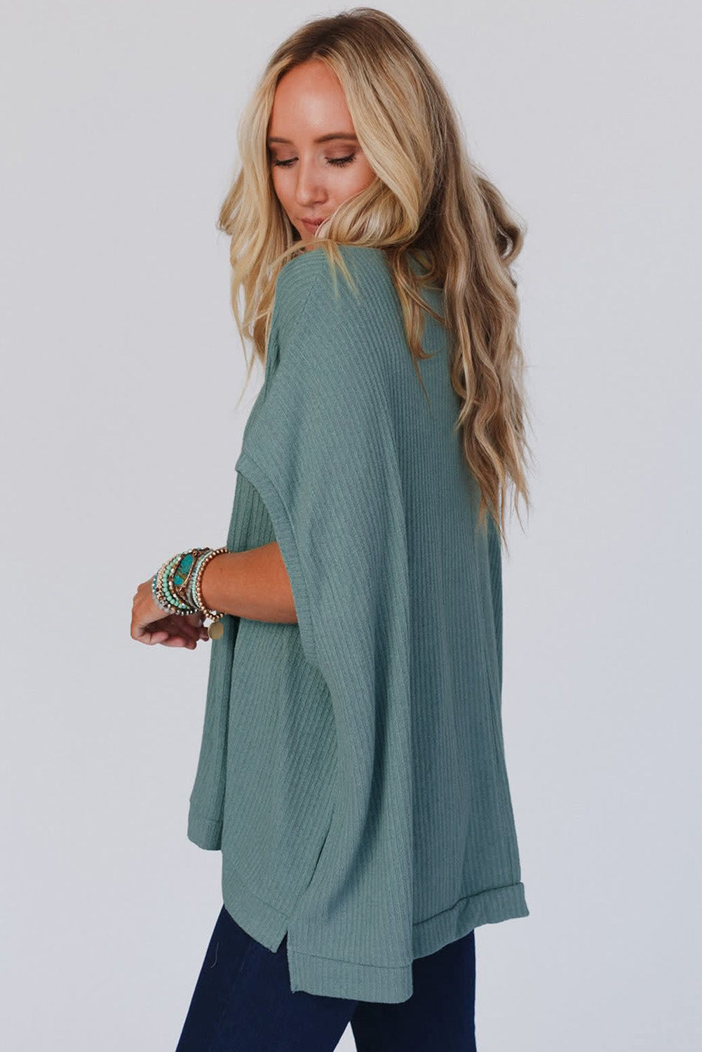 Woman wearing a teal poncho against a white background