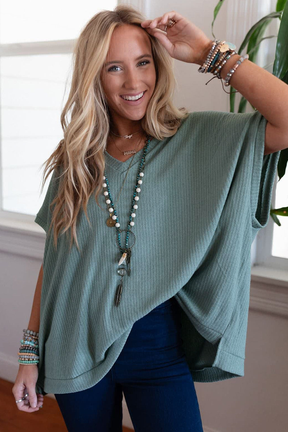 Woman wearing a teal poncho with a neutral background