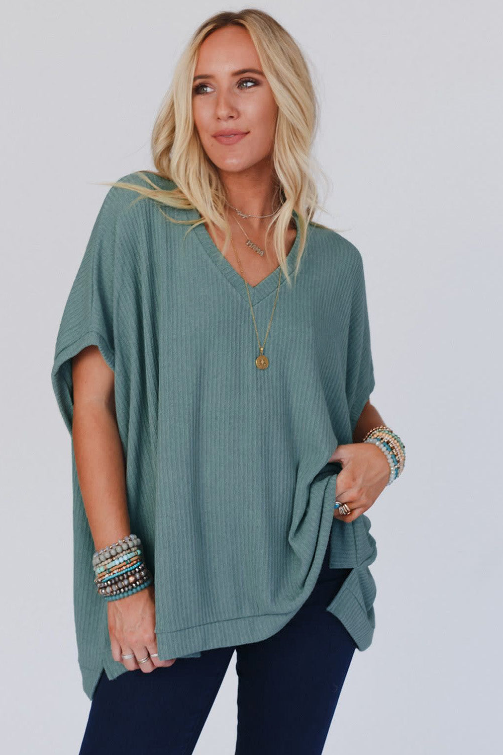 Woman wearing a teal poncho with a plain background
