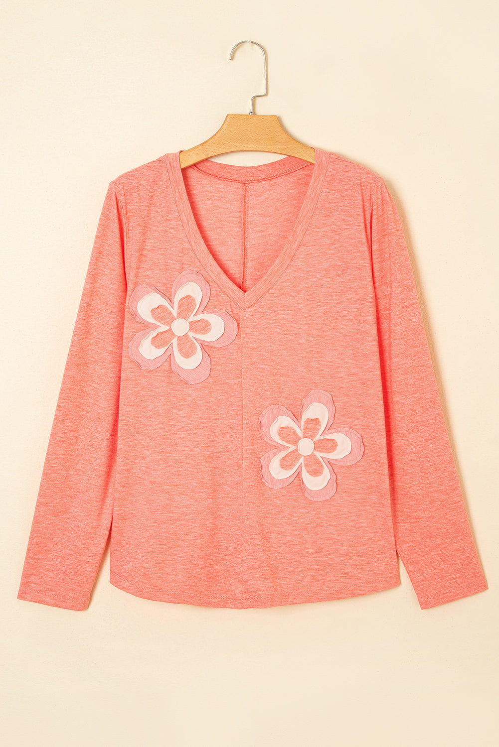 Pink long-sleeve top with white floral designs on a beige background