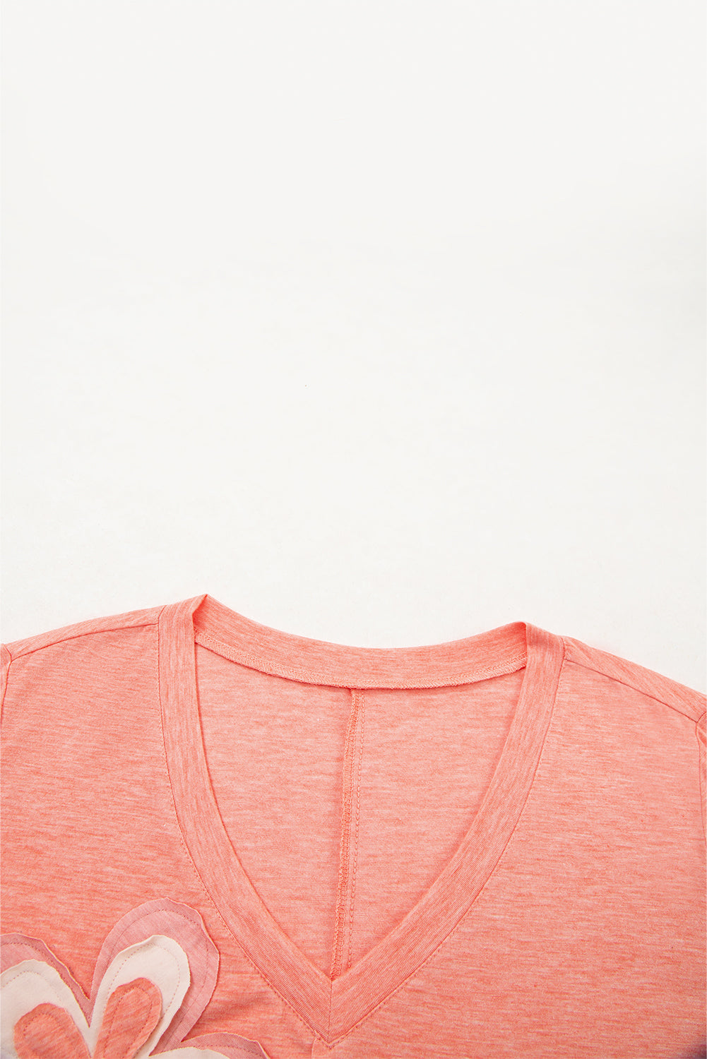 Close-up of a coral-colored shirt with a floral design on a white background