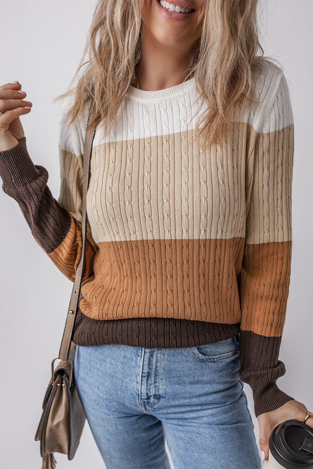 Person wearing a striped sweater with brown, beige, and white colors on a plain background