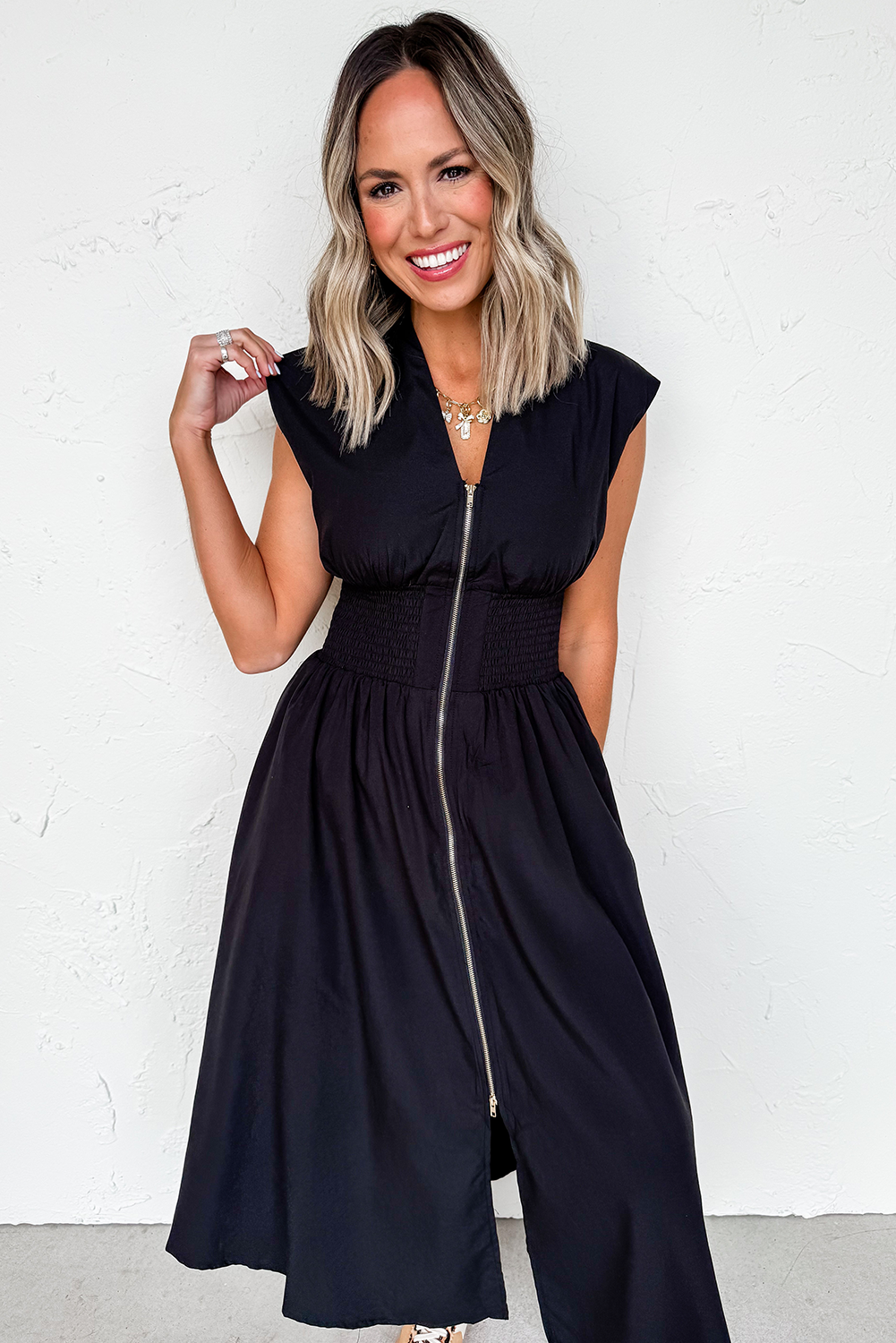 Woman wearing a black dress with a zipper detail against a white background