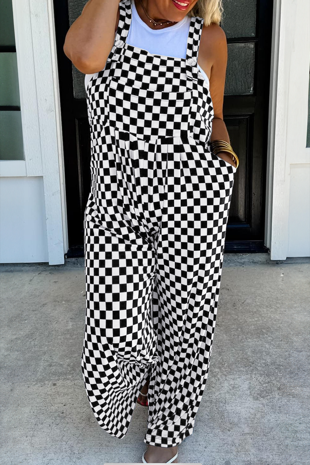 Person wearing a black and white checkered dress standing outside a building.
