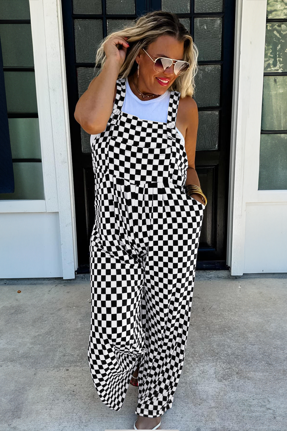 Woman wearing a black and white checkered dress standing outside a building.
