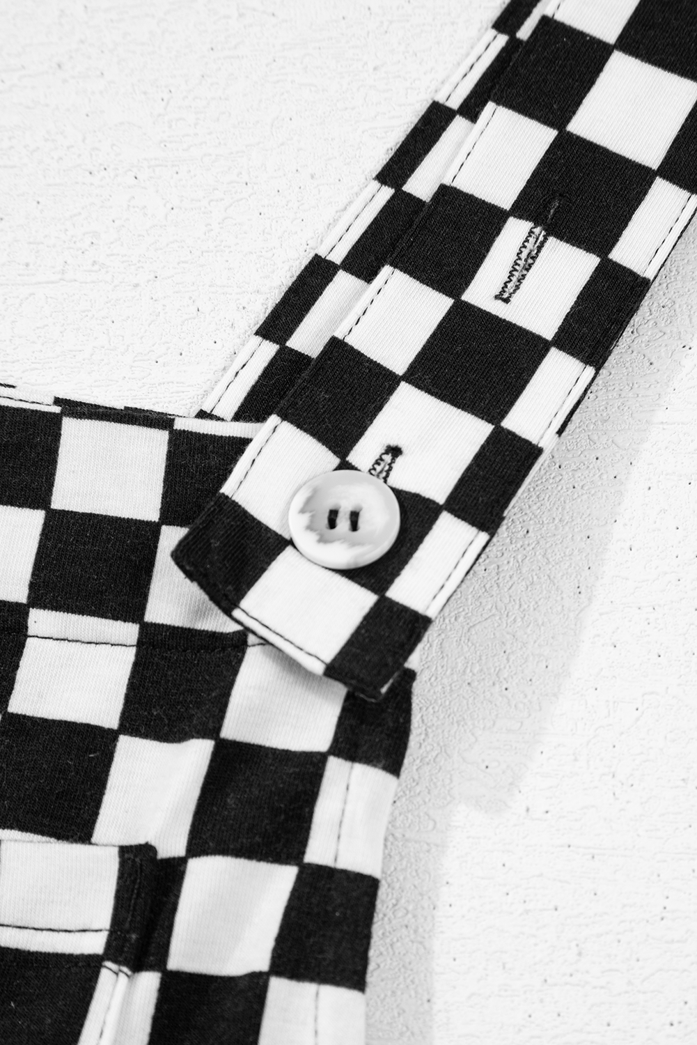 Black and white checkered fabric with a button on a textured background