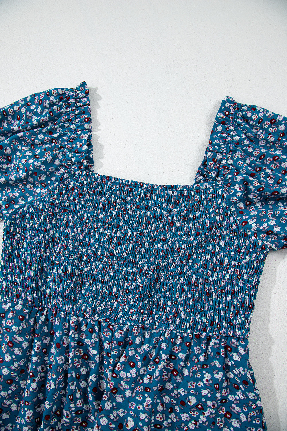 Blue floral dress with ruffled shoulders on a white background