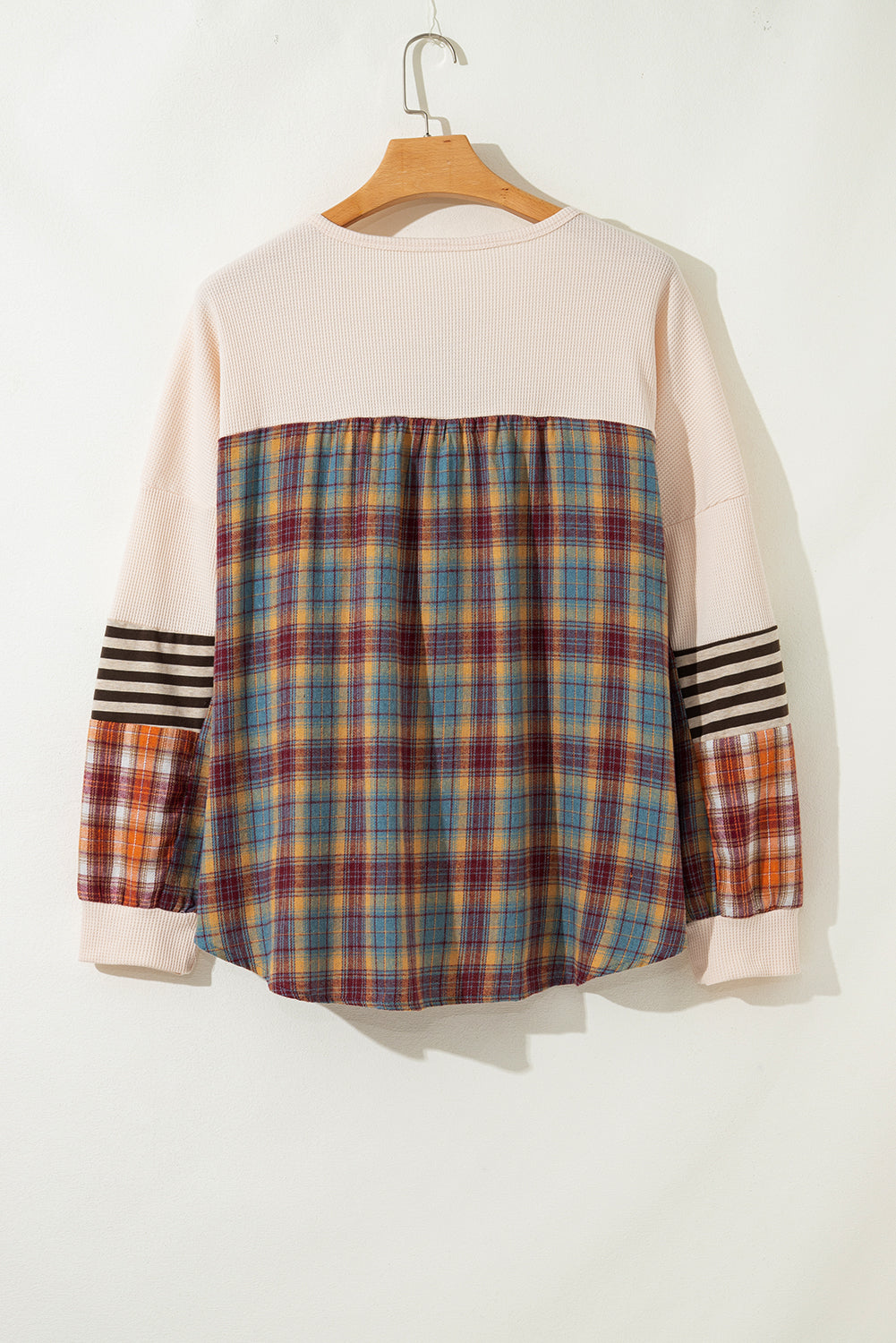 Plaid shirt with striped sleeves on a hanger against a white background