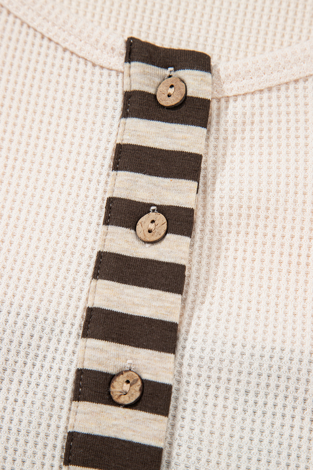 Close-up of a striped fabric with wooden buttons on a textured beige background