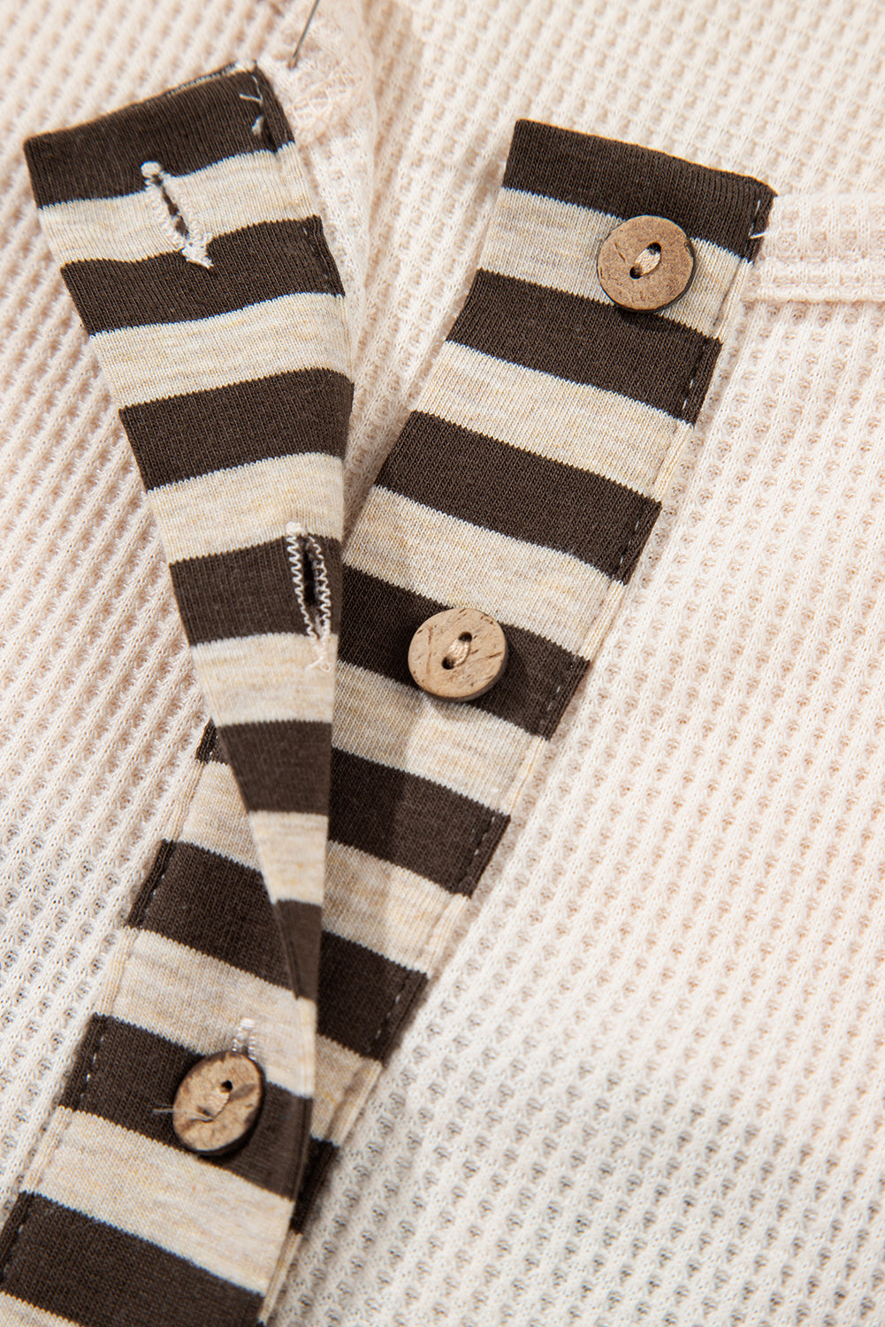 Black and white striped arm warmers with wooden buttons on a textured beige background