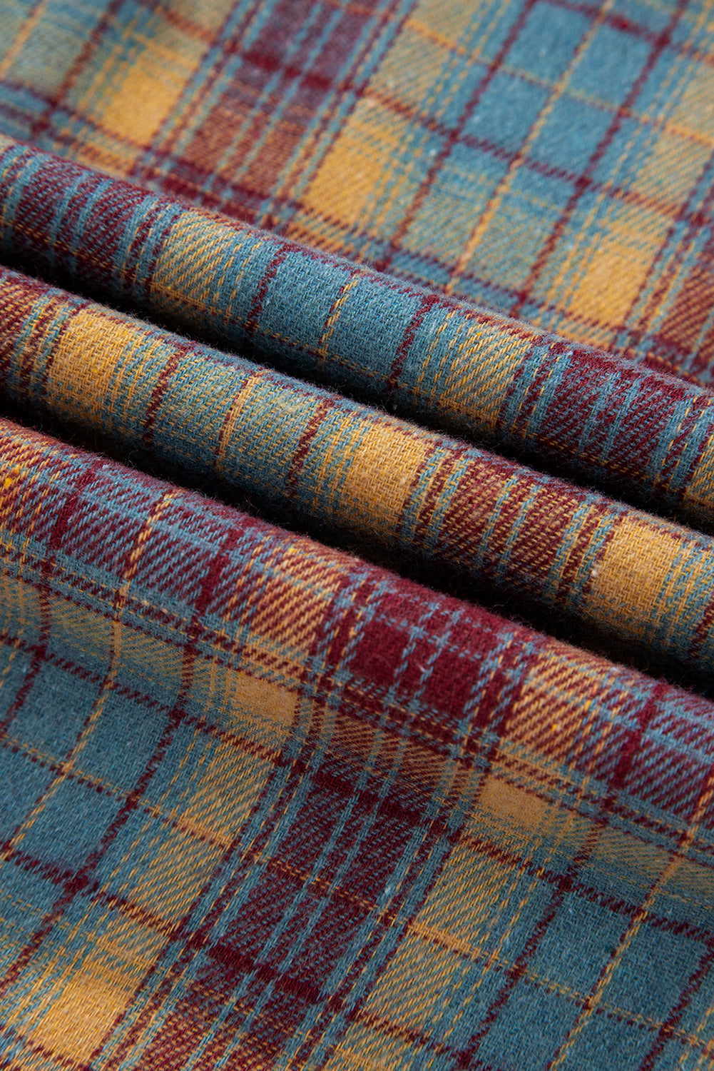 Close-up of plaid fabric with red, blue, and yellow colors.