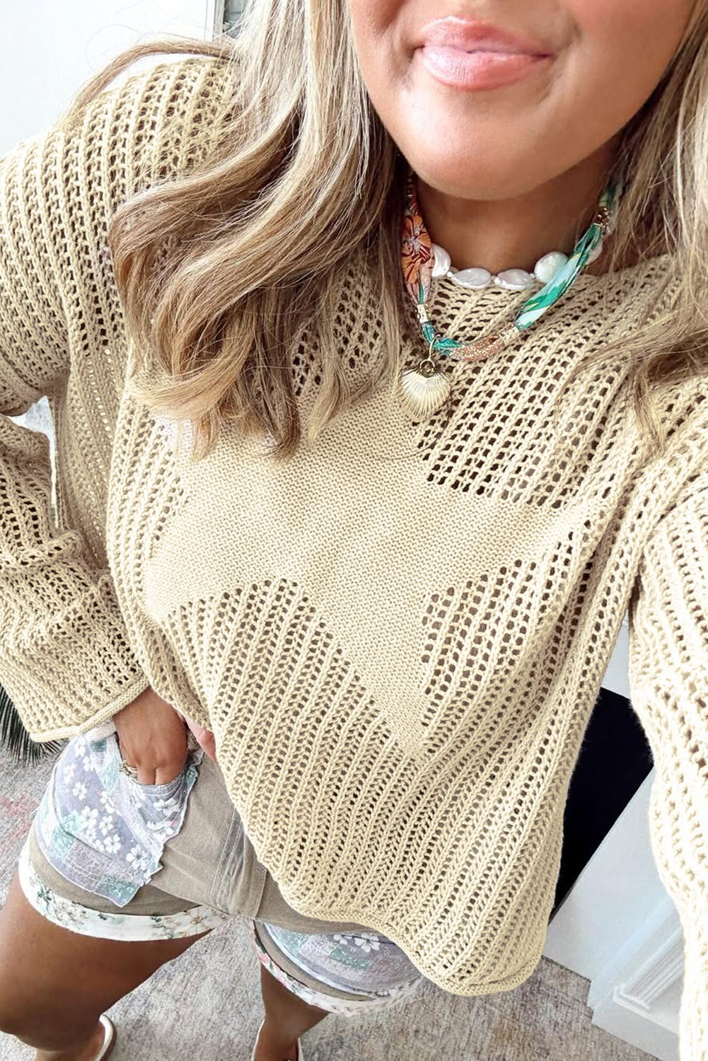 Person wearing a beige knitted sweater with a blurred background