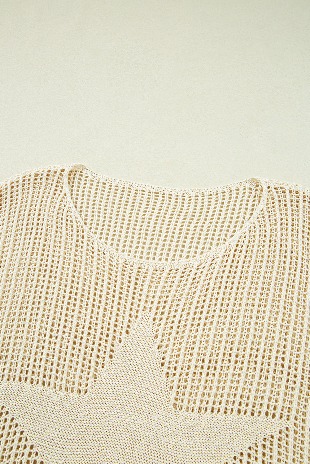 Close-up of a textured beige fabric with star patterns on a light green background