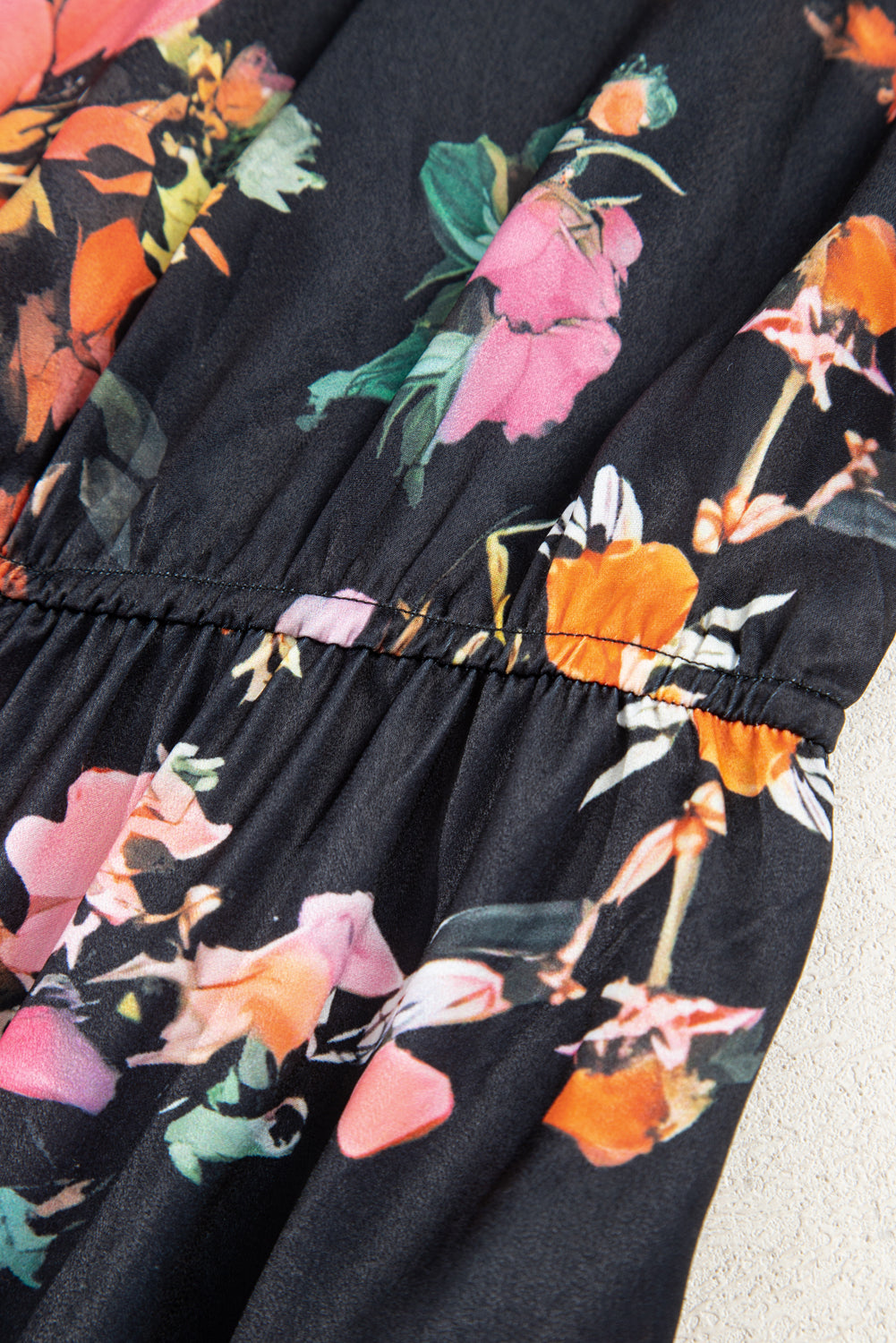 Close-up of a black dress with colorful floral pattern on a light background