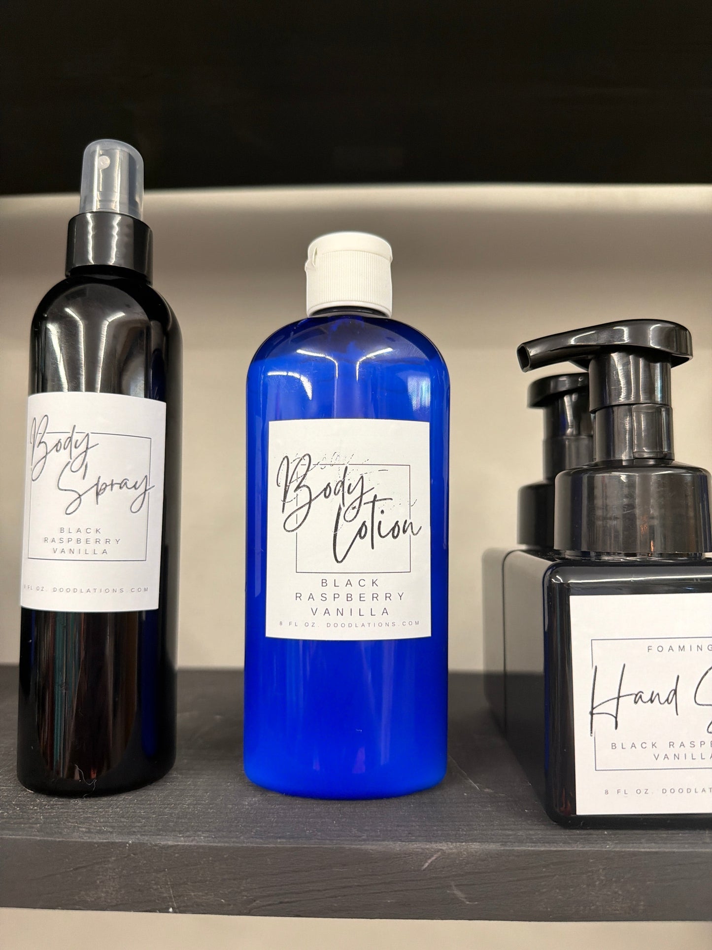 Doodlations Coffee Bar & Boutique blue bottle of Black Raspberry Vanilla body lotion, 8oz, with a white flip-top cap.