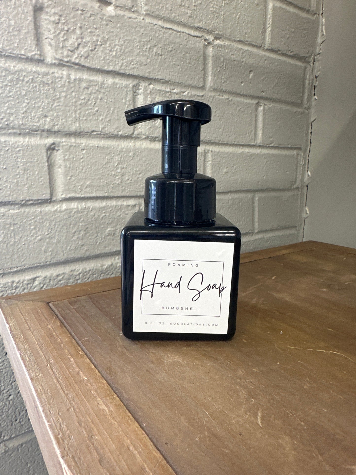 Doodlations Coffee Bar & Boutique Bombshell foaming hand soap in a black square bottle with a white label.