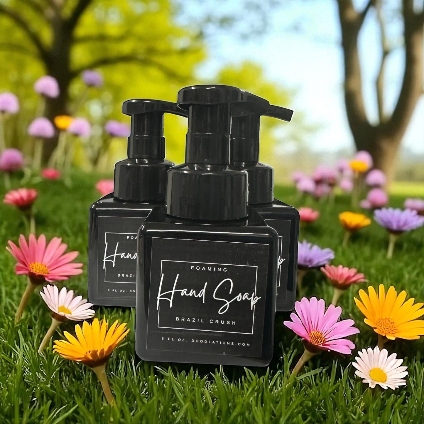 Doodlations Coffee Bar & Boutique Brazilian Crush foaming hand soap in black bottles, set in a grassy field with colorful daisies.