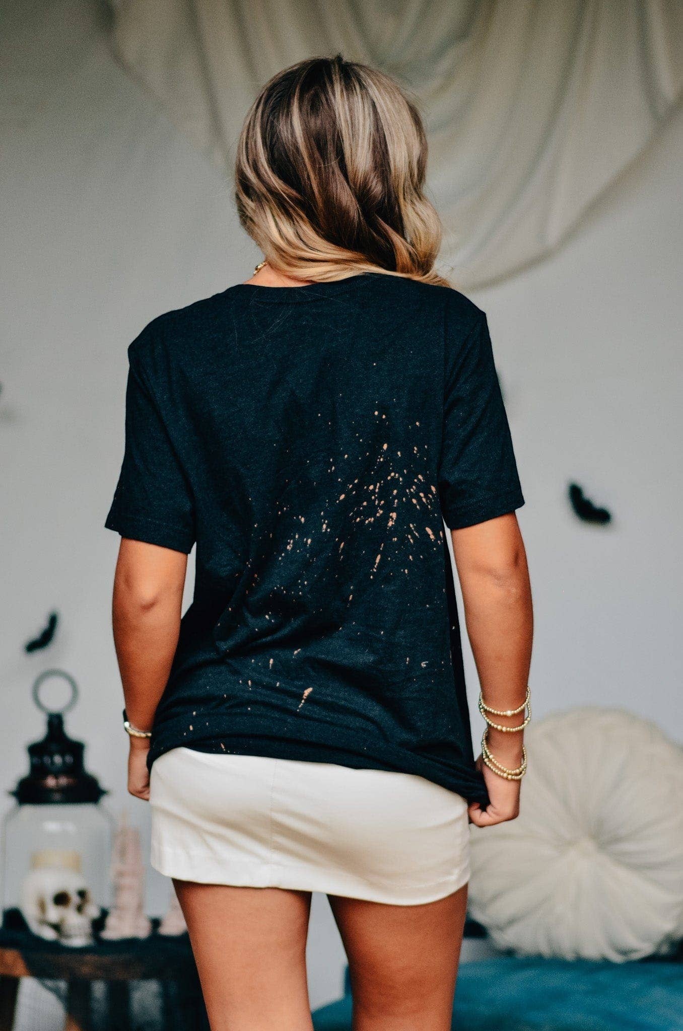 Doodlations Coffee Bar & Boutique black bleached t-shirt with splatter effect worn by a woman from the back view