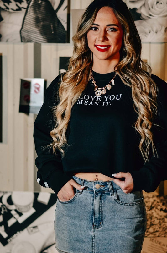 Woman wearing Doodlations Coffee Bar & Boutique black crew neck sweatshirt with Love You Mean It graphic text