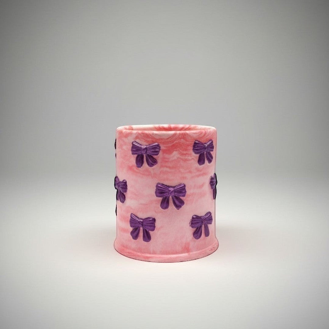 Doodlations Coffee Bar & Boutique Bow Hand Poured Concrete Candle in pink with purple bows. Soy blend wax.