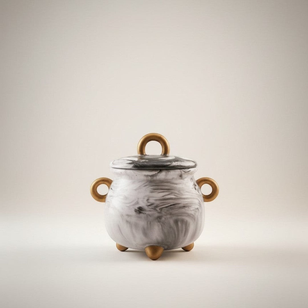 Doodlations Coffee Bar & Boutique cauldron concrete candle with gold handles and feet, marbled grey and black design.