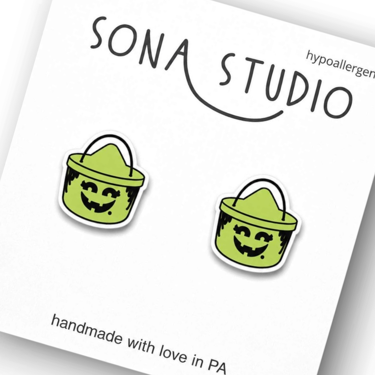 Doodlations Coffee Bar & Boutique retro green witch bucket Halloween stud earrings on a Sona Studio display card.