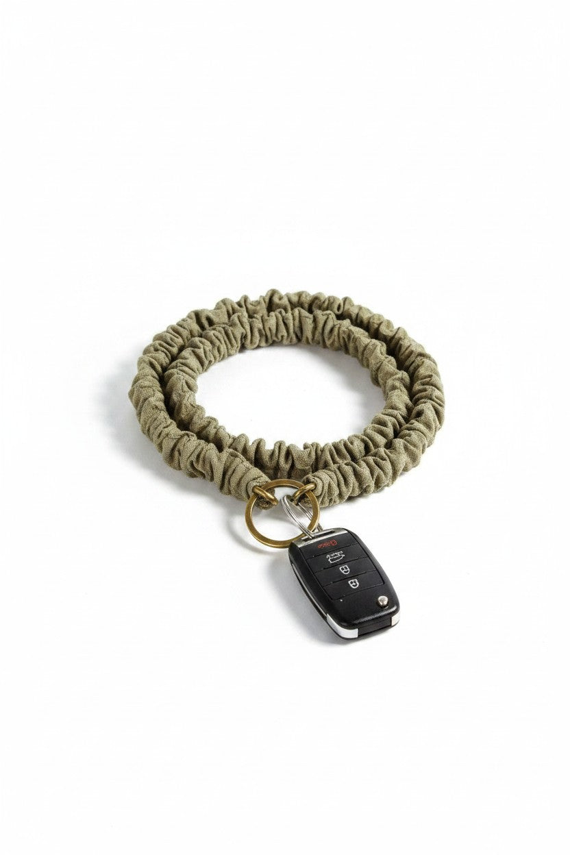 Doodlations Coffee Bar & Boutique moss green crinkled cotton fabric lanyard with a gold ring holding a car key fob.