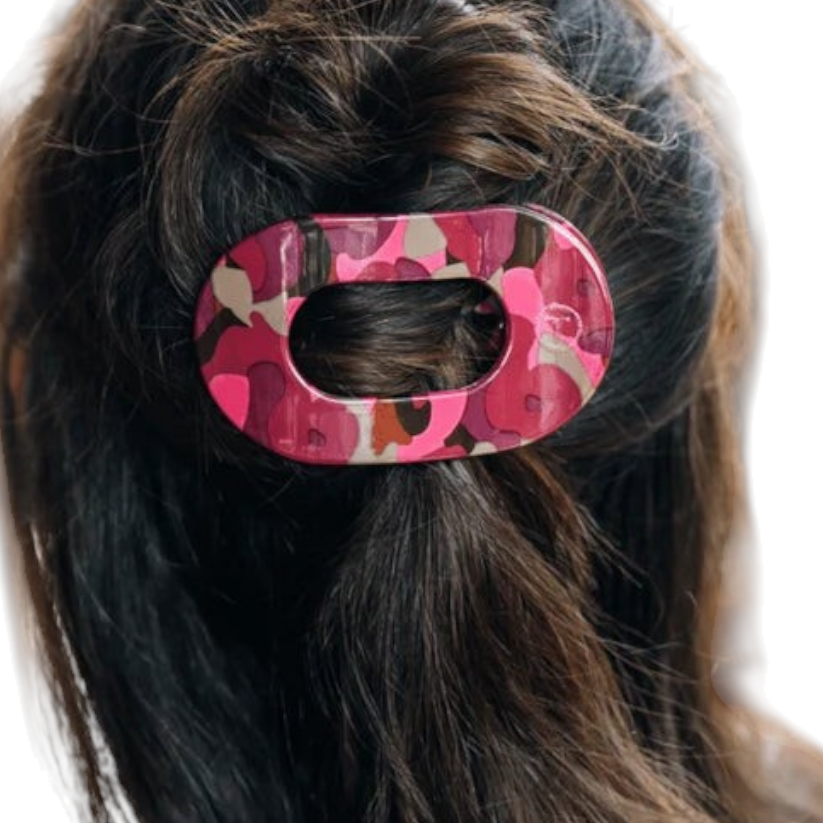 Doodlations Coffee Bar & Boutique Teleties flat round hair clip in a pink and brown camouflage pattern on dark hair.