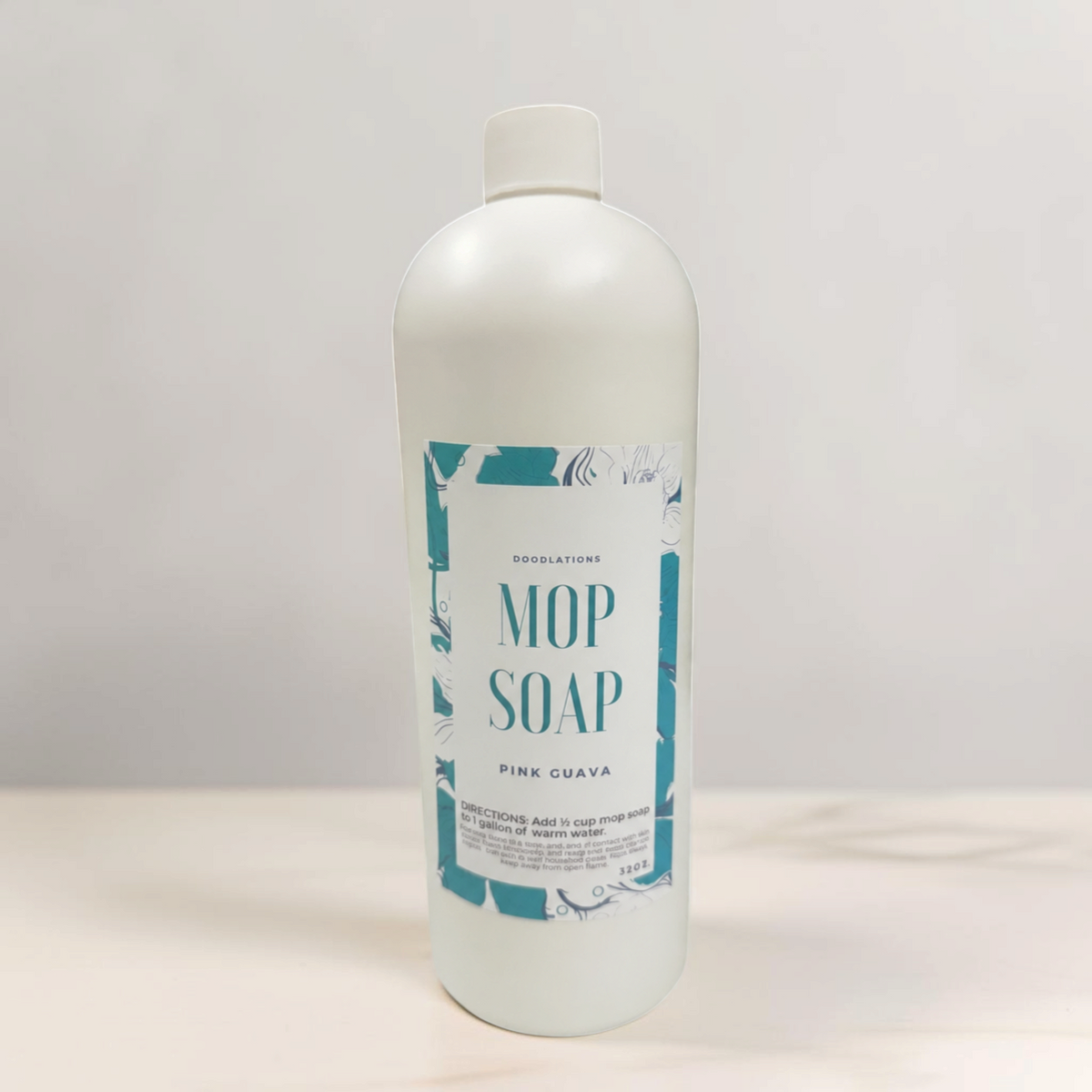Doodlations Coffee Bar & Boutique Pink Guava concentrated mop soap bottle on a marble counter with laundry in background