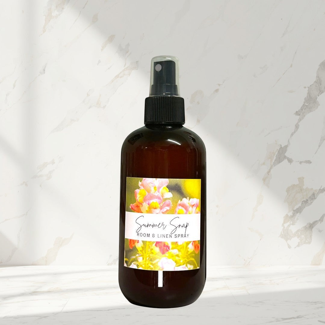 Doodlations Room & Linen Spray in Summer Snap scent, amber bottle with floral label. Bright floral-fruity fragrance.
