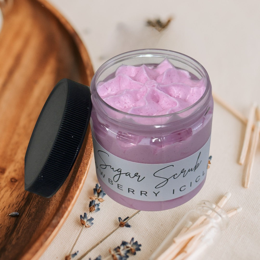 Snowberry Icicles sugar scrub in a clear jar with a black lid. Pink exfoliating body scrub.