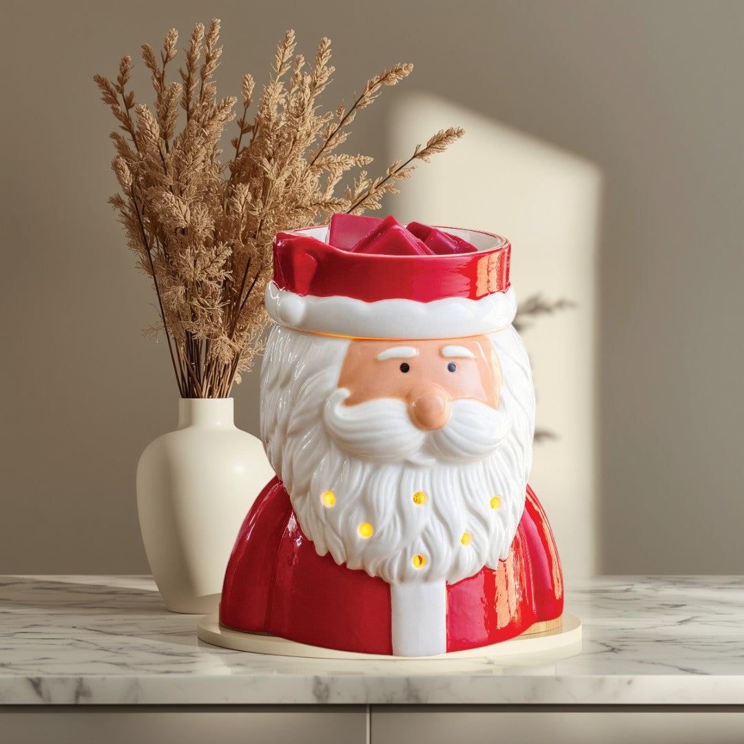 St. Nick fragrance warmer shaped like Santa Claus, with red suit and white beard, glowing warmly.