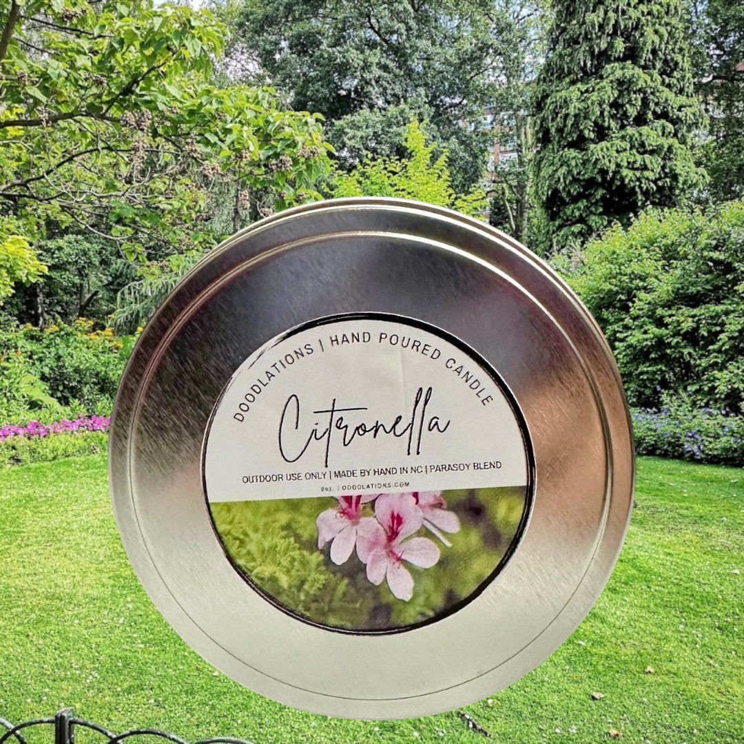 Citronella outdoor candle in a silver tin with a label featuring pink flowers and greenery.