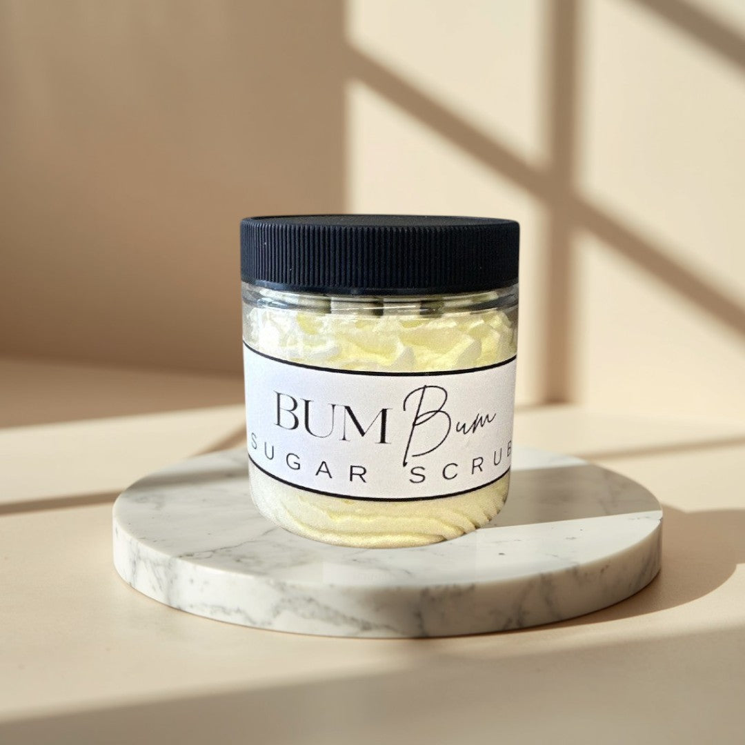 Bum Bum Sugar Scrub in a clear jar with a black lid. Yellow scrub with a creamy texture.