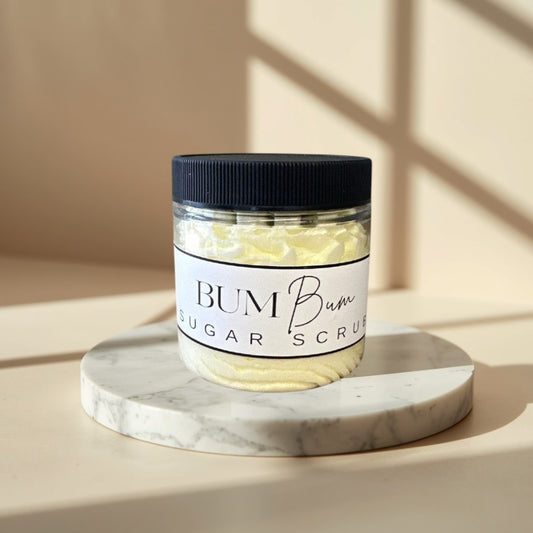 Bum Bum Sugar Scrub in a clear jar with a black lid. Yellow scrub with a creamy texture.