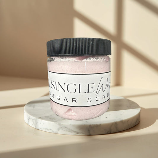 A Single Wish sugar scrub in a clear jar with a black lid. Pink scrub.