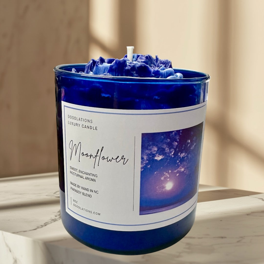 Moonflower luxury candle in a cobalt blue jar with a wax flower topper.