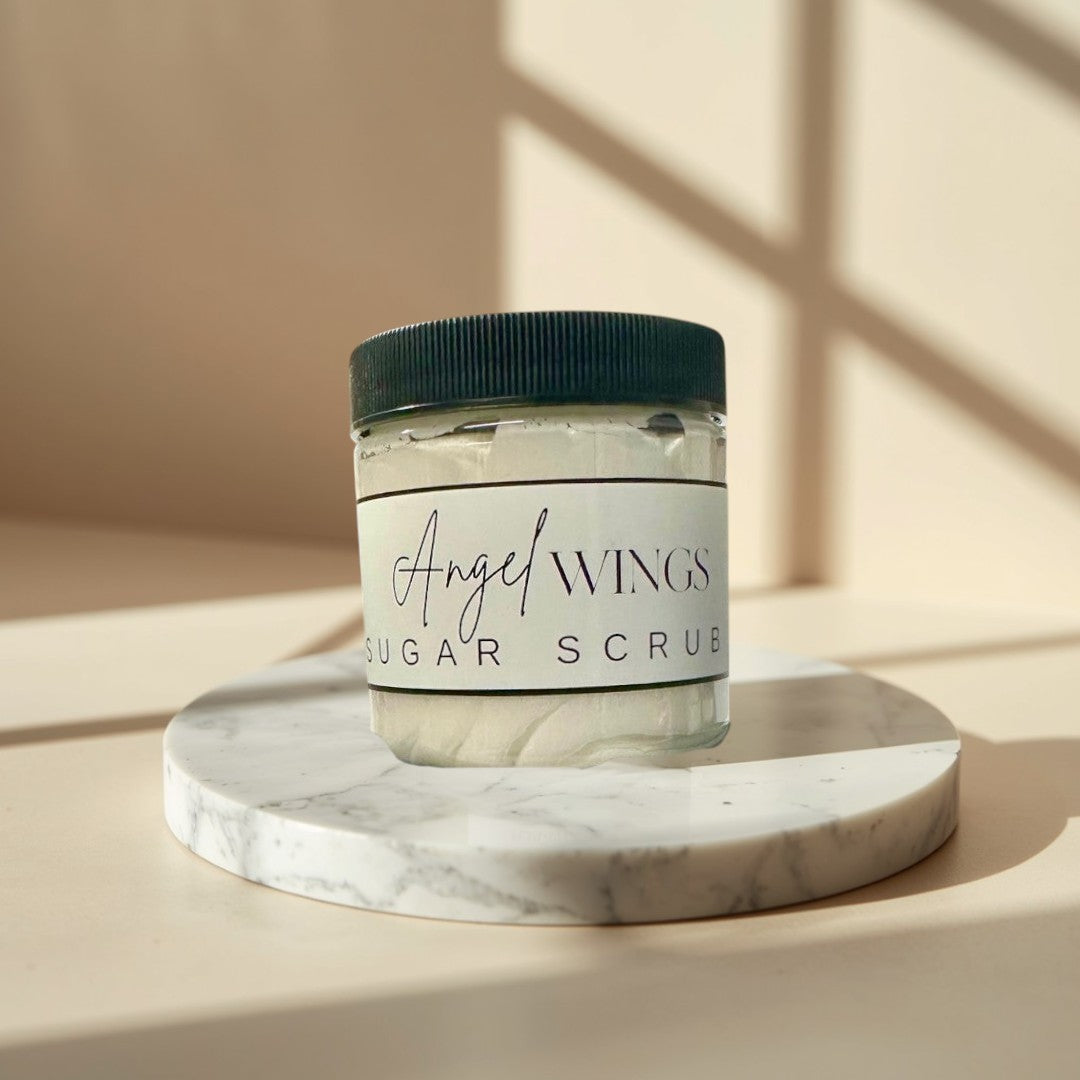 Angel Wings sugar scrub in clear jars with black lids. White scrub with visible sugar crystals.