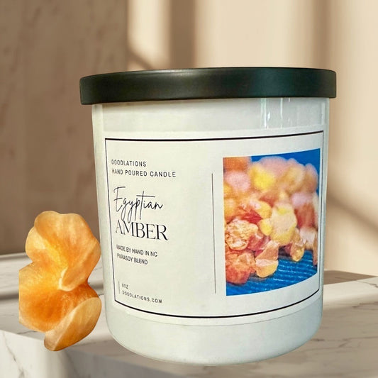 Doodlations Egyptian Amber hand-poured soy blend candle in a white jar with a black lid.