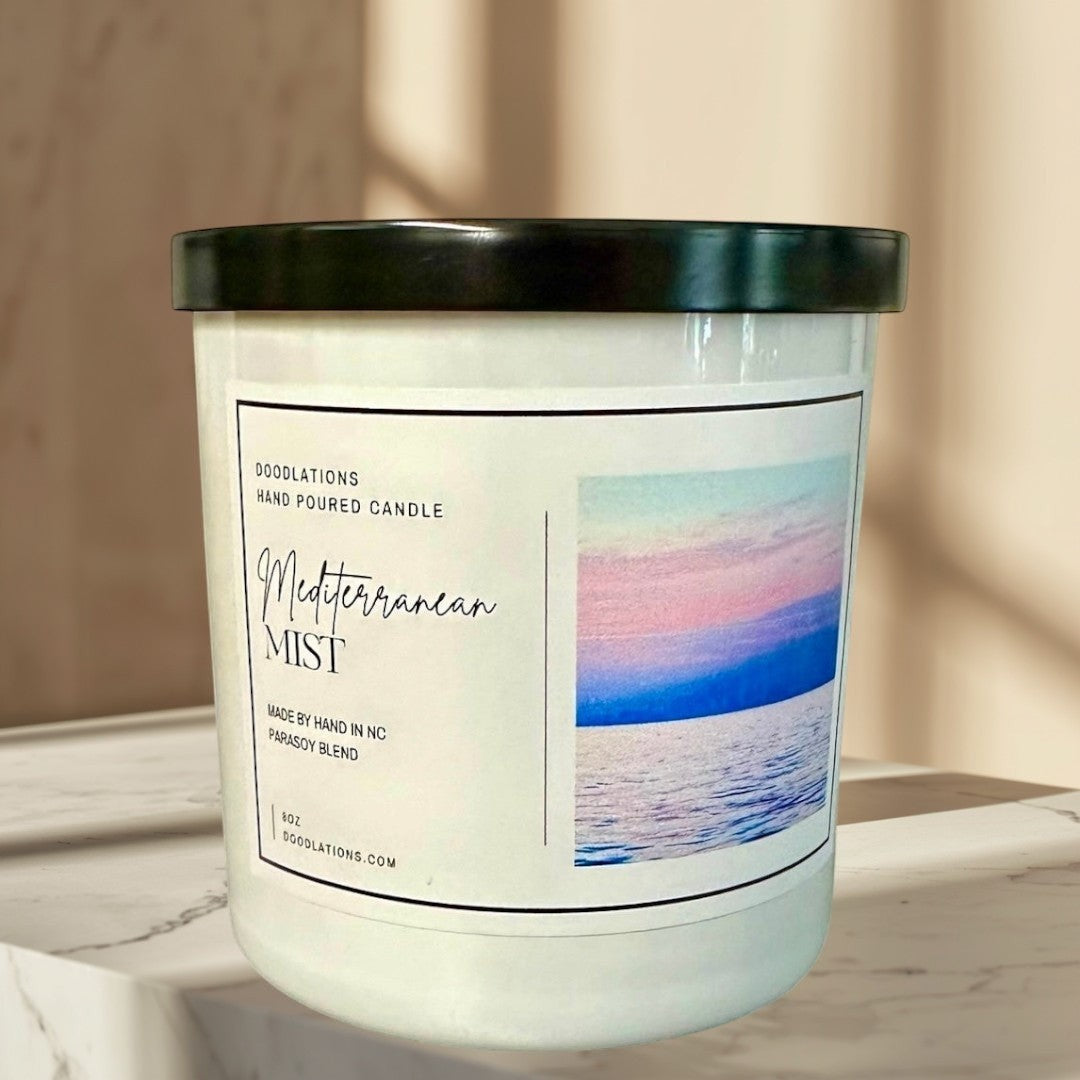 Mediterranean Mist hand-poured soy blend candle with a coastal sunset image.