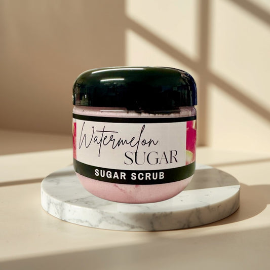 Watermelon Sugar Scrub in a clear jar with a black lid. Pink scrub with watermelon imagery on the label.