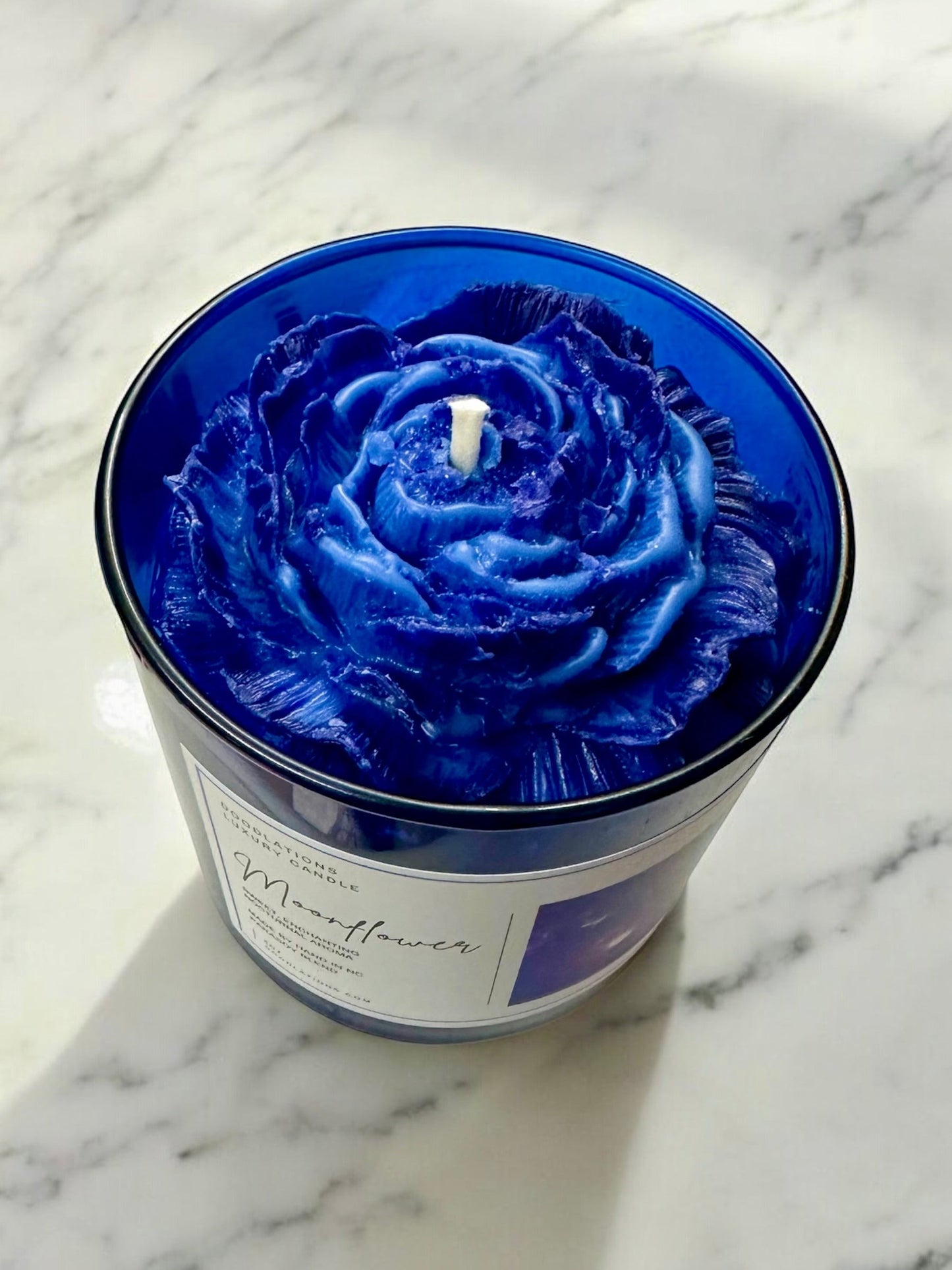 Doodlations Coffee Bar & Boutique Moonflower luxury candle in a cobalt blue jar with a wax flower topper.
