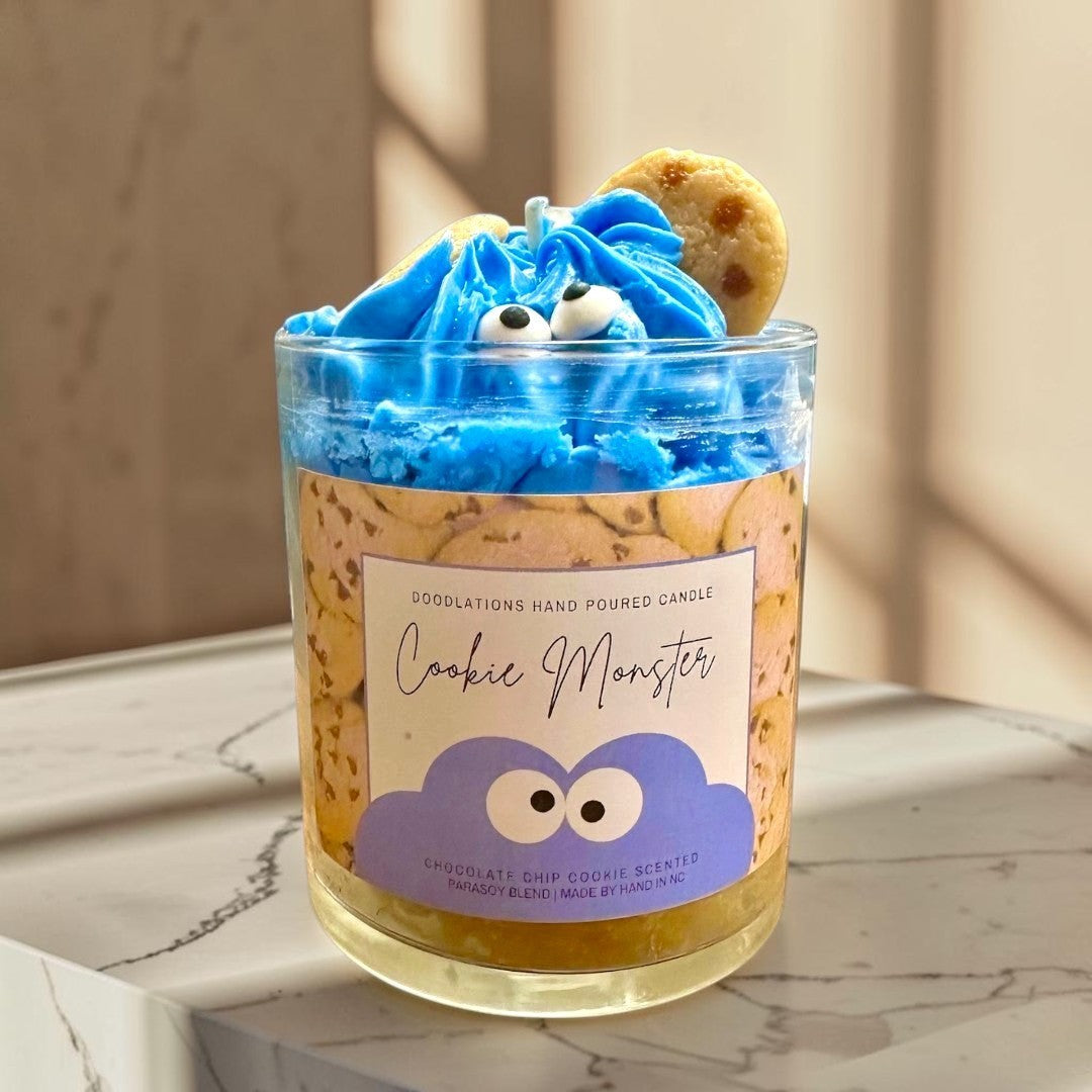 Doodlations Coffee Bar & Boutique Cookie Monster candle with blue frosting, candy eyes, and cookie accents. Chocolate chip cookie scented.