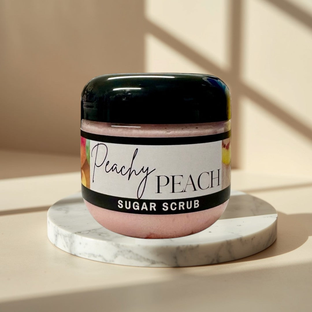 Peachy Peach sugar scrub in a clear jar with a black lid. Pink scrub with peach imagery.