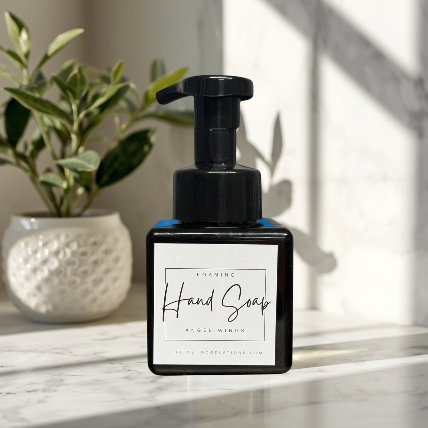 Angel Wings foaming hand soap in a black bottle with a white label.