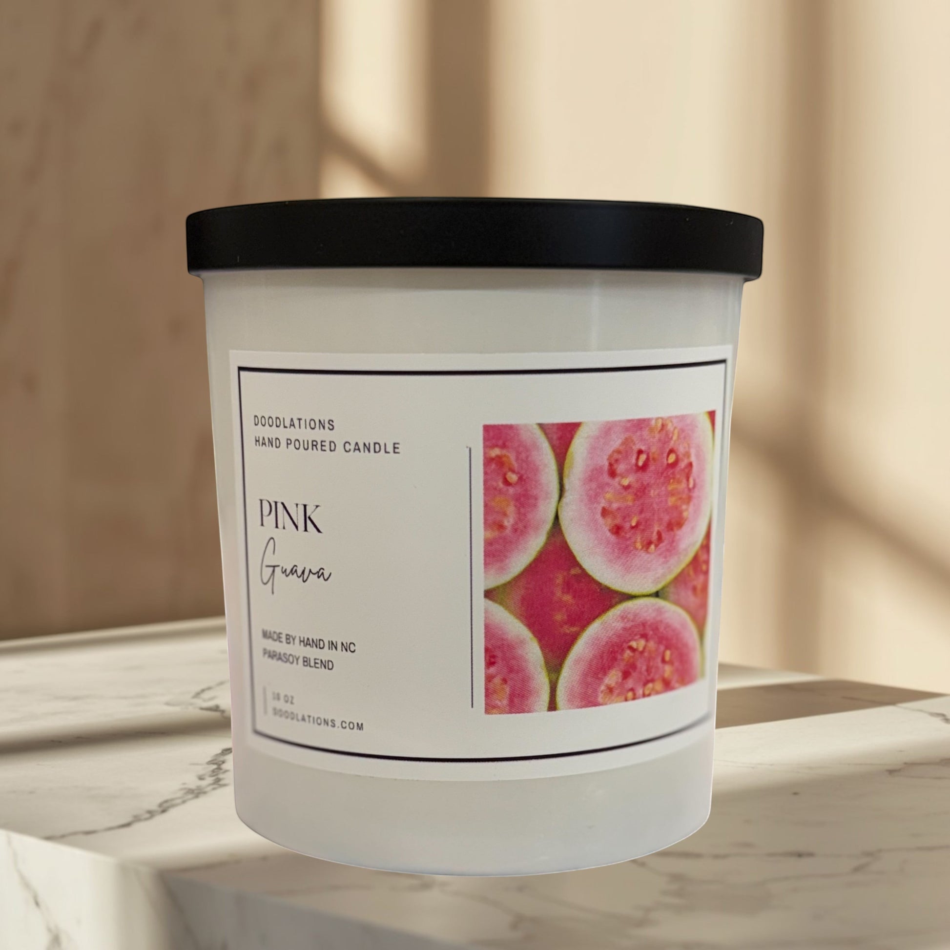 Doodlations Coffee Bar & Boutique Pink Guava hand-poured soy blend candle with a tropical beach background.