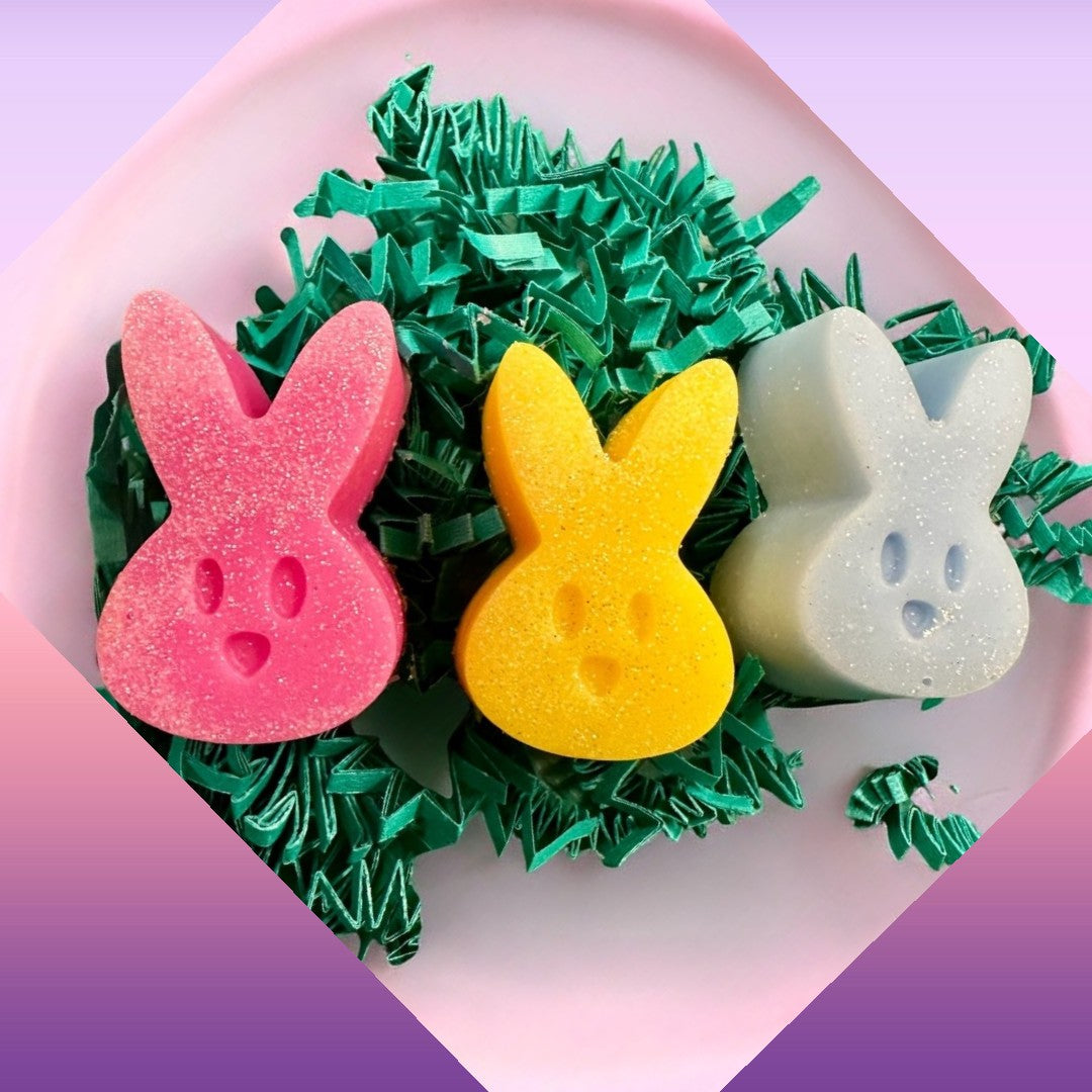 Peeps wax melts in pink, yellow, and blue bunny shapes with glitter, nestled in green crinkle paper.